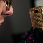 Nahaufnahme einer sprechenden Person an einem goldfarbenen Studiomikrofon