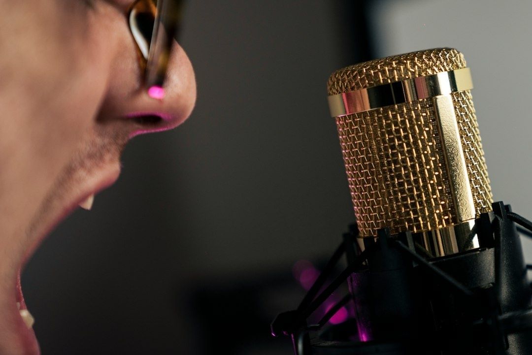 Nahaufnahme einer sprechenden Person an einem goldfarbenen Studiomikrofon